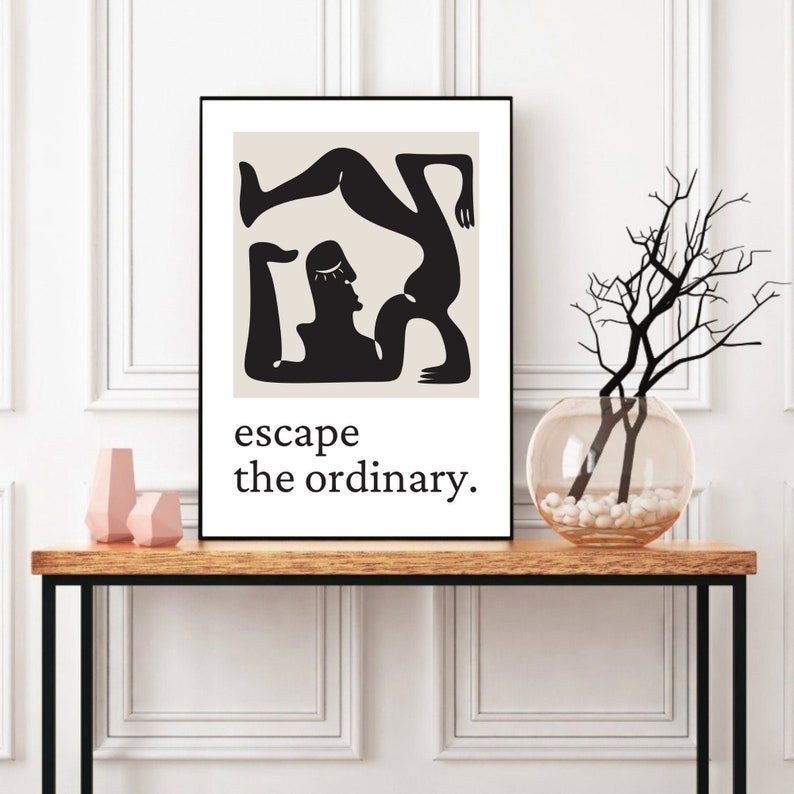 May include: Black and white minimalist art print featuring a stylized figure in a yoga pose. The print has a beige background and the text "escape the ordinary."