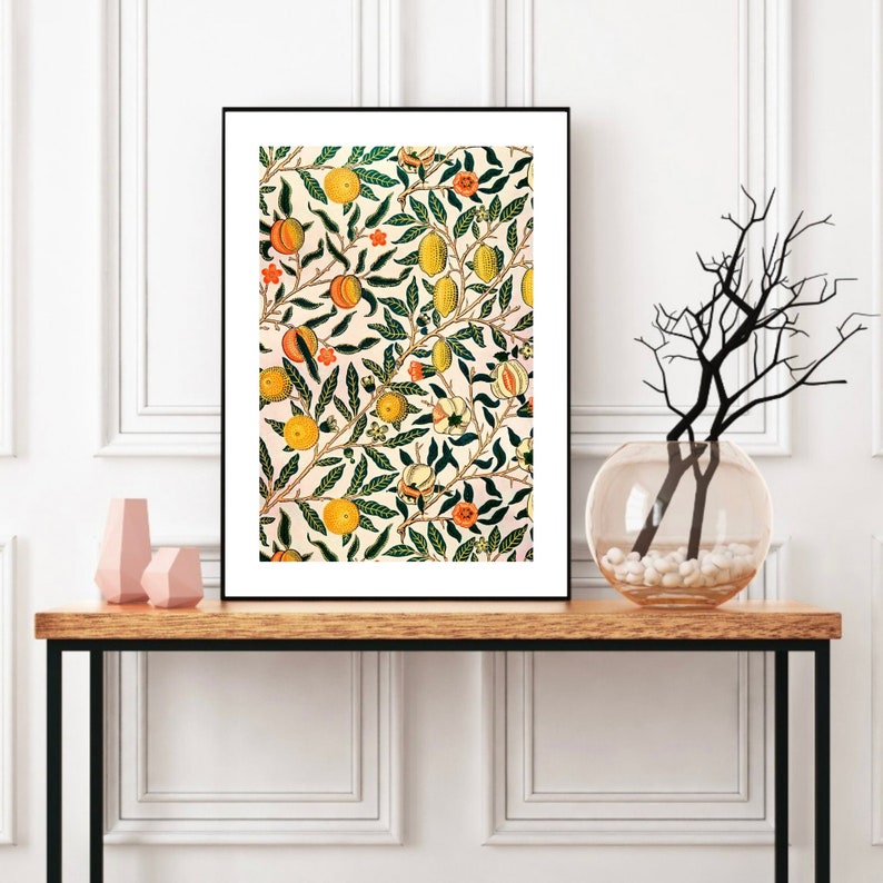 K&ouml;nnte beinhalten: Ein gerahmter Druck eines Vintage-Blumenmusters mit einem sich wiederholenden Design aus gr&uuml;nen Bl&auml;ttern, orangefarbenen und gelben Fr&uuml;chten und wei&szlig;en Bl&uuml;ten auf einem hellrosa Hintergrund.