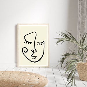 Pu&ograve; includere: Un disegno in bianco e nero di un viso con gli occhi chiusi su uno sfondo crema. Il disegno &egrave; incorniciato in una cornice di legno chiaro.