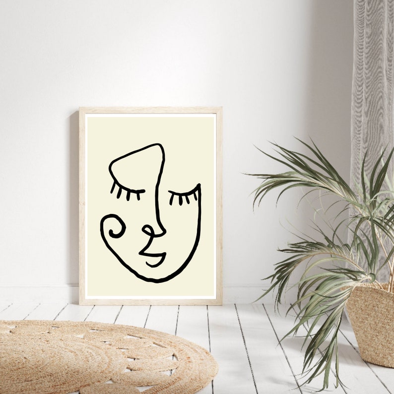 Pu&ograve; includere: Un disegno in bianco e nero di un viso con gli occhi chiusi su uno sfondo crema. Il disegno &egrave; incorniciato in una cornice di legno chiaro.