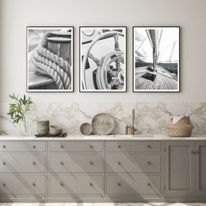 Puede incluir: Tres fotografías en blanco y negro de un velero. La primera imagen muestra un primer plano de una cuerda envuelta alrededor de una uña. La segunda imagen muestra un primer plano del timón del barco. La tercera imagen muestra la cubierta del velero con la vela en el fondo.