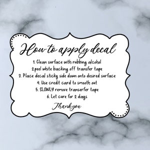 May include: White card with black text outlining how to apply a decal. The instructions include cleaning the surface with rubbing alcohol, peeling the backing off the transfer tape, placing the decal sticky side down, smoothing it out with a credit card, slowly removing the transfer tape, and letting it cure for two days. The card ends with the word "Thank you".