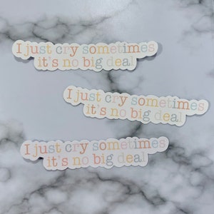 Op de afbeelding: Drie stickers met de tekst "I just cry sometimes it's no big deal" in verschillende pastelkleuren op een marmeren achtergrond.