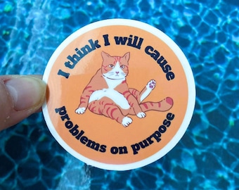 Puede incluir: Pegatina de gato naranja y blanco con el texto "Creo que voy a causar problemas a propósito".