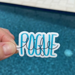 May include: A blue and white sticker with the text "Pogue Life" in a cursive font. The sticker is held in a hand over a blue swimming pool.