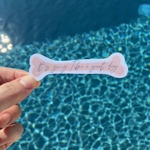 May include: A pink bone-shaped sticker with the text "It's going to be a great day" written in cursive.