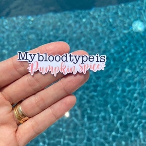 May include: A white sticker with the text "My blood type is Pumpkin Spice" in black and pink lettering.