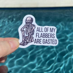 May include: A white sticker with a cartoon skeleton sitting down and the text "ALL OF MY FLABBERS ARE GASTED".