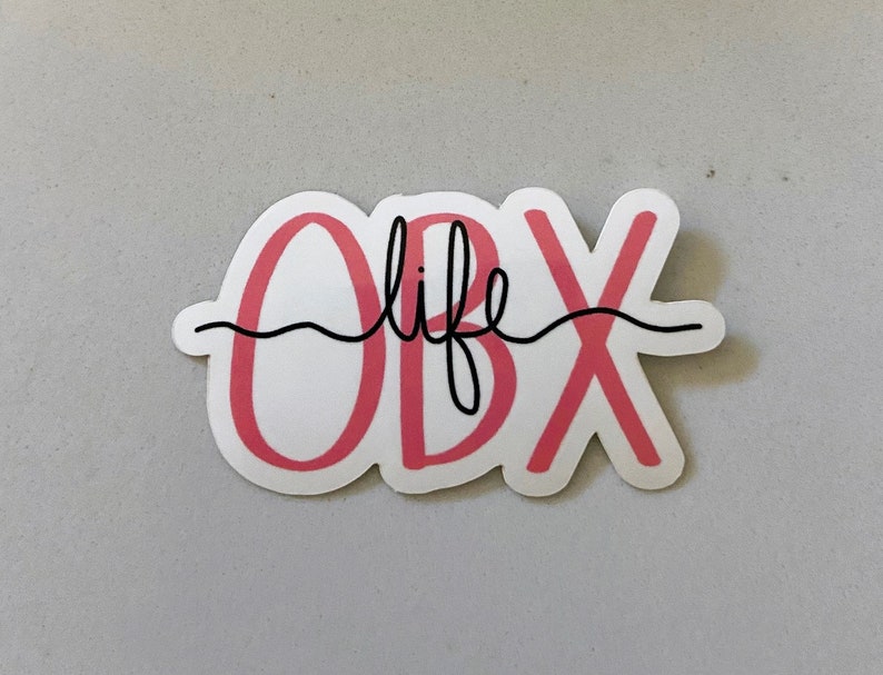 May include: Pink and white sticker with the text "OBX life" in black cursive lettering.