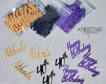 May include: An assortment of paper cutouts in various colors, including gold, black, and purple. The cutouts feature the name "Nikale", the number "40th", and the phrase "Happy Birthday" in a cursive font. The cutouts are in small plastic bags.