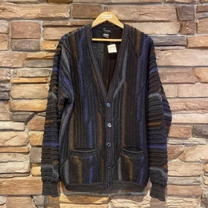 May include: A brown, blue and grey striped cardigan with a v-neck and button closure. The cardigan has two pockets and a label that reads "Tasso".