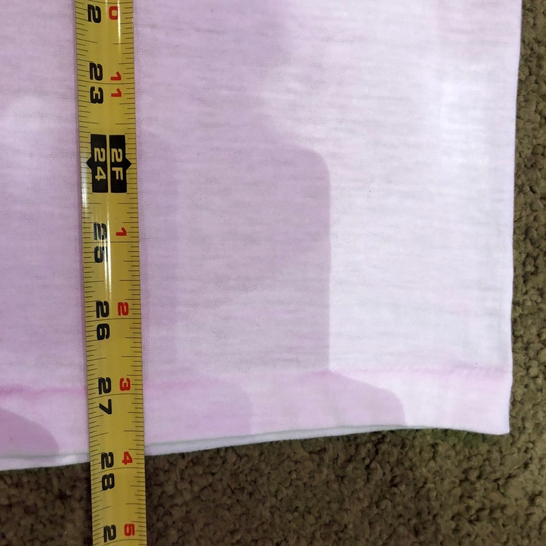 May include: A close-up of a yellow measuring tape with black markings, measuring 28 inches. The tape is placed against a light pink fabric.