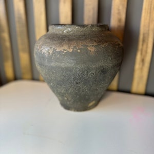 May include: A dark brown, round, ceramic pot with a textured surface.