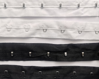 May include: Four strips of fabric with metal hooks. Two strips are white and two strips are black.