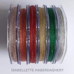 May include: Six spools of metallic ribbon in various colors, including silver, gold, red, green, and copper. The ribbon is wound around clear plastic spools.