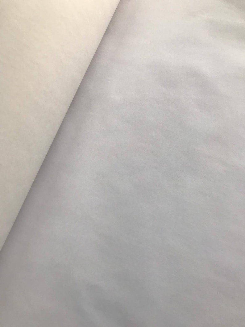 May include: A close-up shot of two sections of paper. One section is a light cream color, and the other is a light gray. The paper is slightly textured and appears to be rolled.