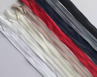 May include: Assortment of zipper closures in various colors, including white, beige, cream, red, navy blue, gray, and black. The zippers are laid out in a diagonal line on a white background.