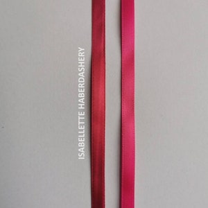 May include: Two satin ribbons, one in a deep red color and the other in a bright pink color. The ribbons are both about 1/2 inch wide and are shown against a white background.