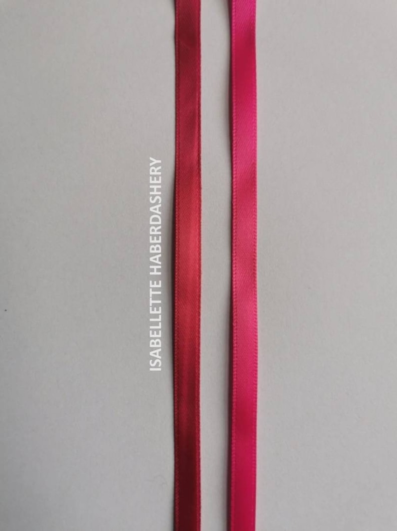 May include: Two satin ribbons, one in a deep red color and the other in a bright pink color. The ribbons are both about 1/2 inch wide and are shown against a white background.