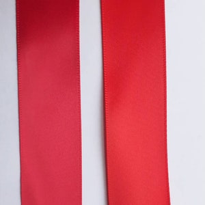 May include: Two red satin ribbons, one slightly darker than the other, are shown against a white background.