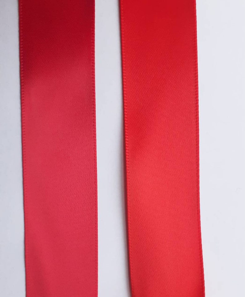 May include: Two red satin ribbons, one slightly darker than the other, are shown against a white background.