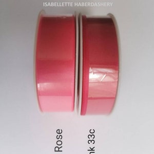 May include: Two spools of ribbon, one in a light pink shade labeled "Rose" and the other in a darker pink shade labeled "Pink 33c".