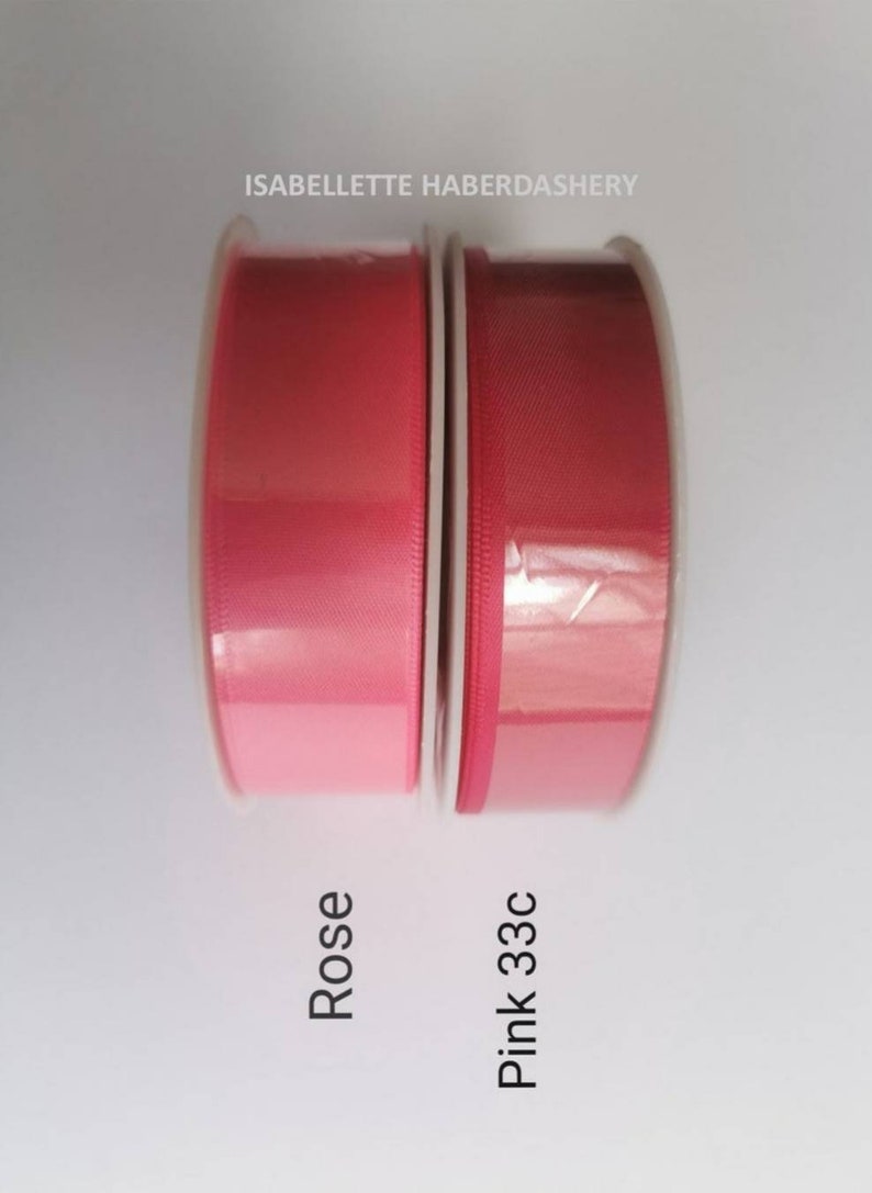 May include: Two spools of ribbon, one in a light pink shade labeled "Rose" and the other in a darker pink shade labeled "Pink 33c".