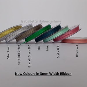 May include: A selection of 3mm wide ribbon spools in various colors, including gold, silver, teal, mint, dusky pink, and rose gold. The text "New Colors in 3mm Width Ribbon" and "Isabellette Haberdashery" are visible on the image.