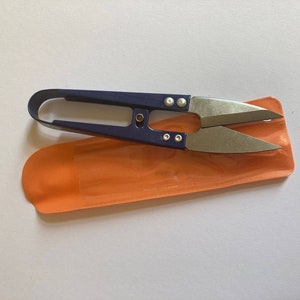 Könnte beinhalten: Eine kleine, blaue Schere mit silberner Klinge in einem orangefarbenen Etui.