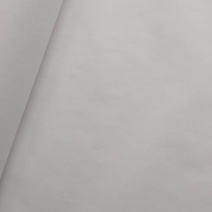 May include: A close-up shot of a folded, light gray fabric. The fabric has a smooth texture and appears to be made of a soft material. The folds create shadows and depth, highlighting the fabric's texture and color.