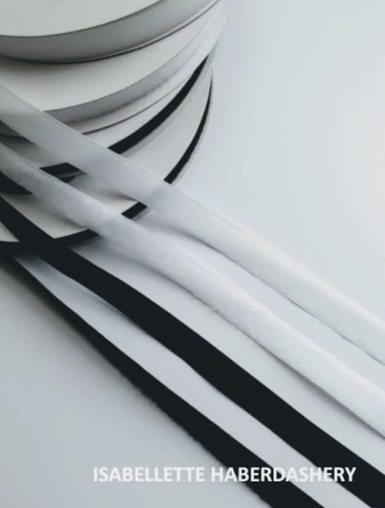 May include: Close-up of three rolls of black and white fabric trim. The trim is arranged in a stack, with the black trim on top and the white trim on the bottom. The trim is likely used for sewing or crafting projects.