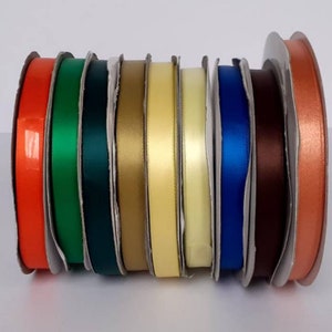 May include: Assortment of colorful satin ribbon spools in orange, green, gold, yellow, light yellow, blue, brown, and copper.