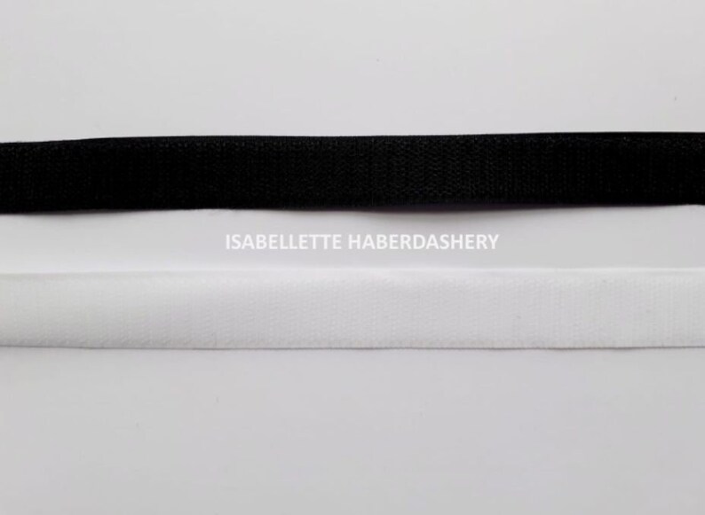 May include: Black and white hook and loop tape, also known as Velcro.  The tape is shown on a white background.  ISABELLETTE HABERDASHERY is printed below the tape.