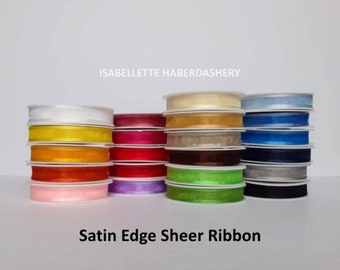 May include: A collection of satin edge sheer ribbon in various colors, including white, yellow, orange, red, purple, green, brown, beige, blue, and gray. The ribbon is stacked in rows and labeled "Satin Edge Sheer Ribbon".