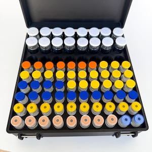 May include: A black case filled with small glass vials with colorful caps. The caps are white, orange, yellow, blue, and peach. The vials are arranged in rows and columns.