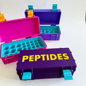 May include: A collection of colorful, small, plastic cases. The cases are purple, pink, and teal, with yellow text that reads "PEPTIDES". The cases are open, revealing a teal interior with multiple circular compartments.