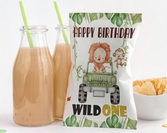 Könnte beinhalten: Eine weiße Snacktüte mit einer Aquarellillustration eines Löwen in einem grünen Jeep und eines Affen, mit dem Text "HAPPY BIRTHDAY" und "WILD ONE" in Braun und Gold. Zwei Glasflaschen mit hellgrünen Strohhalmen und eine Schale mit Chips.