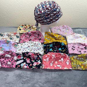 May include: A collection of 14 colorful patterned scrub hats with various cartoon characters and designs. The hats are made of soft, breathable fabric and are perfect for nurses, doctors, and other healthcare professionals.