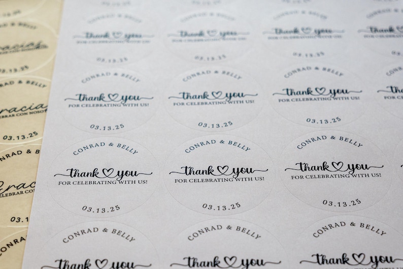 Peut inclure: Gros plan sur des autocollants ronds blancs avec du texte noir. Les autocollants indiquent "Thank you" avec un c&oelig;ur, "For celebrating with us!" et la date "03.13.25". Les noms "Conrad & Belly" sont &eacute;galement imprim&eacute;s.