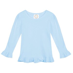 May include: A light blue long-sleeved shirt with a ruffled hem and ruffled cuffs. The shirt has a round neckline and a small white tag with the text "PB & J" on the front.