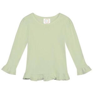 May include: A light green long-sleeved shirt with a ruffled hem and cuffs. The shirt has a round neckline and a small white label with the text "B" on the front.
