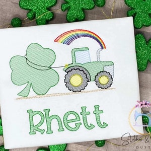May include: A white t-shirt with a green shamrock, a green tractor pulling the shamrock, a rainbow above the tractor, and the name "Rhett" embroidered in green.