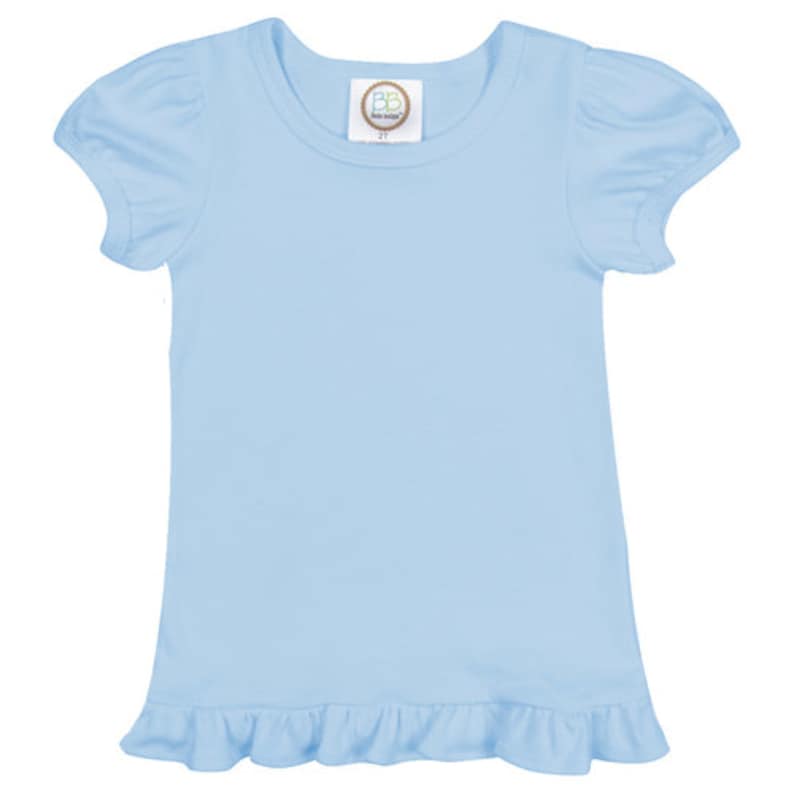 May include: A light blue baby t-shirt with short sleeves and a ruffled hem. The shirt has a small tag with the text "BB Boutique" on the front.