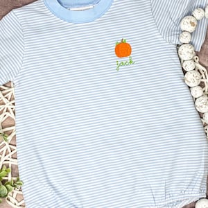 May include: A blue and white striped baby onesie with a small embroidered pumpkin and the name "Jack" on the front.