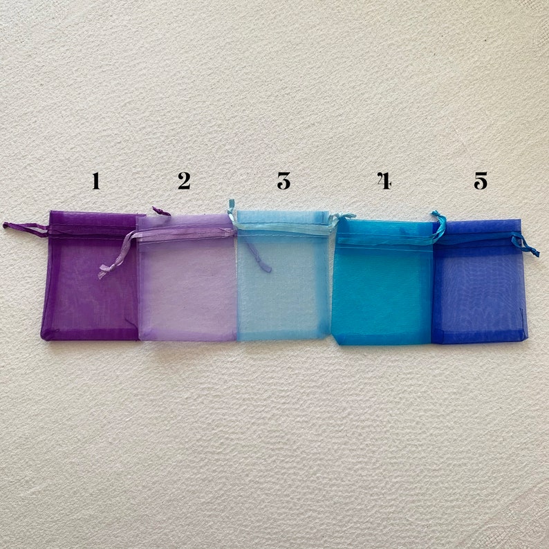 K&ouml;nnte beinhalten: F&uuml;nf kleine Organzas&auml;ckchen in verschiedenen Farben. Die S&auml;ckchen sind mit den Zahlen 1, 2, 5, 1 und 5 beschriftet.
