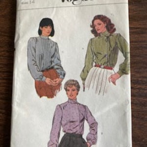 May include: Vintage Vogue sewing pattern number 2611, size 14, for a blouse with a high neck and long sleeves. The pattern shows three different versions of the blouse, one in a light blue fabric, one in a green fabric, and one in a purple fabric.