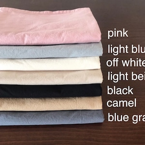 May include: A stack of eight fabric swatches in different colors, including pink, light blue, off white, light beige, black, camel, and blue gray.