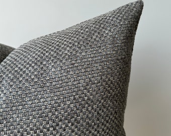 May include: A close-up of a gray and white textured pillow with a diamond pattern. The pillow is made of a soft, woven fabric.