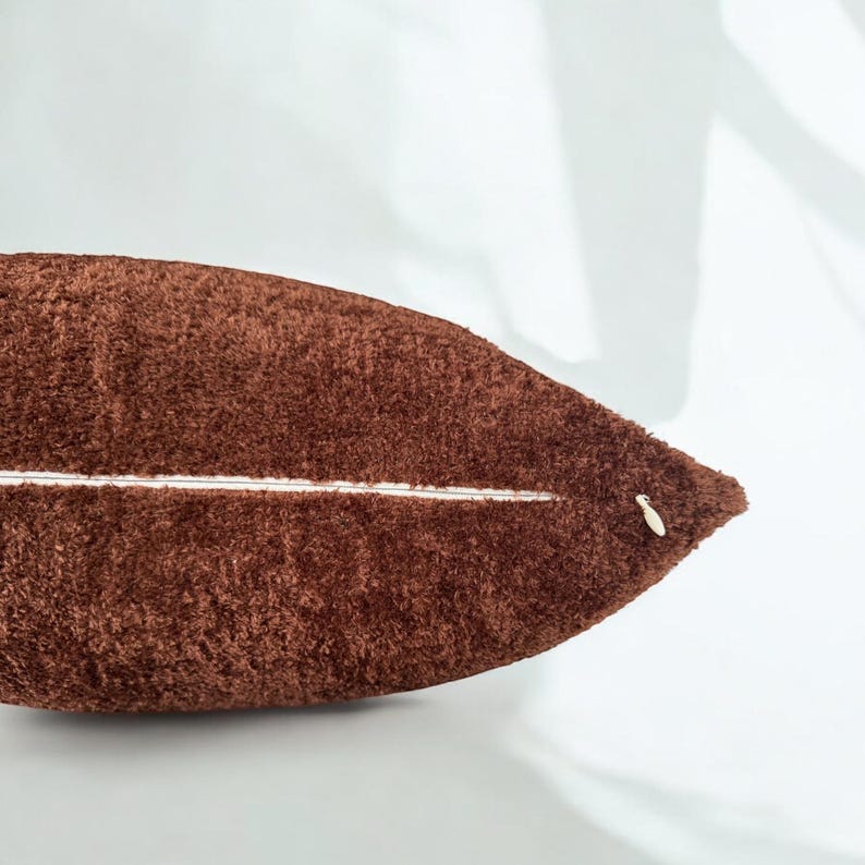 Peut inclure: Un oreiller en peluche marron avec une fermeture &eacute;clair blanche. L'oreiller est doux et moelleux.