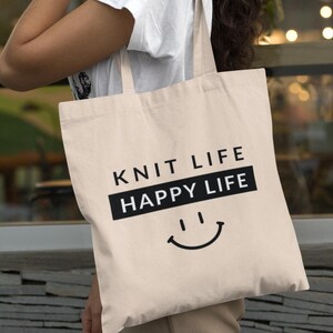 Woman holding tote bag on her shoulder that says "Knit Life Happy Life"